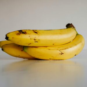 A bunch of fresh yellow bananas stacked elegantly on a smooth white surface, ready to eat.