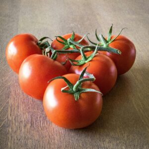 Ripe red tomatoes on a wooden table, showcasing their vibrant color and freshness.