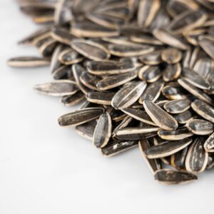 Pile of sunflower seeds displayed on a white surface, perfect for healthy snack themes.